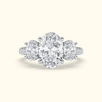 Three-stone diamond ring featuring a central oval diamond flanked by two round diamonds.