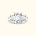Elegant three-stone ring featuring an emerald-cut center diamond with two smaller side diamonds.