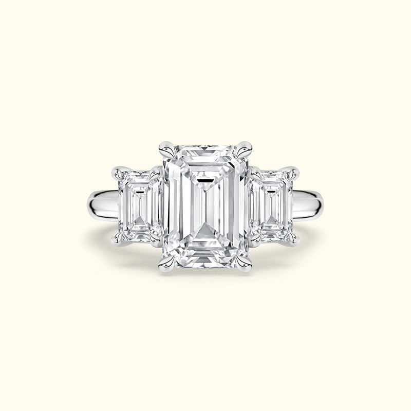 Elegant three-stone ring featuring an emerald-cut center diamond with two smaller side diamonds.