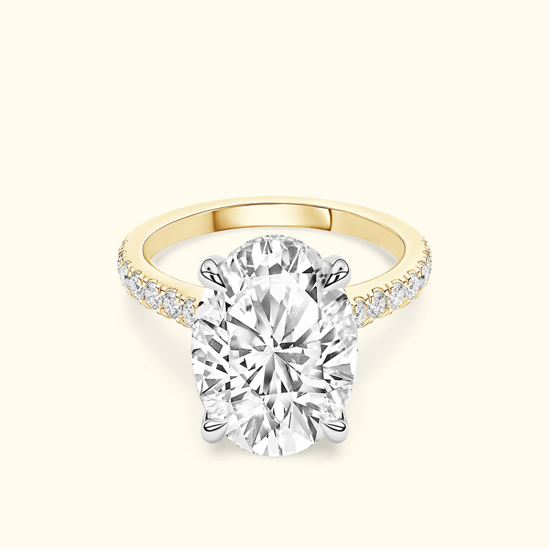 Oval diamond ring with a yellow gold band and smaller diamonds along the sides.