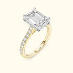 Elegant gold ring featuring a large emerald-cut diamond and smaller accent stones.