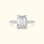 Emerald-cut diamond ring with a delicate band adorned with smaller diamonds.
