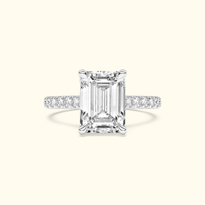 Emerald-cut diamond ring with a delicate band adorned with smaller diamonds.