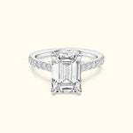 Emerald-cut diamond ring with a sparkling band, set against a light background.