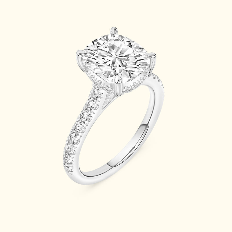 Solitaire diamond engagement ring with a halo setting and pave band in white gold.