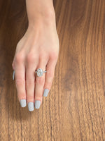 A hand displaying a large, sparkling engagement ring on a wooden surface.
