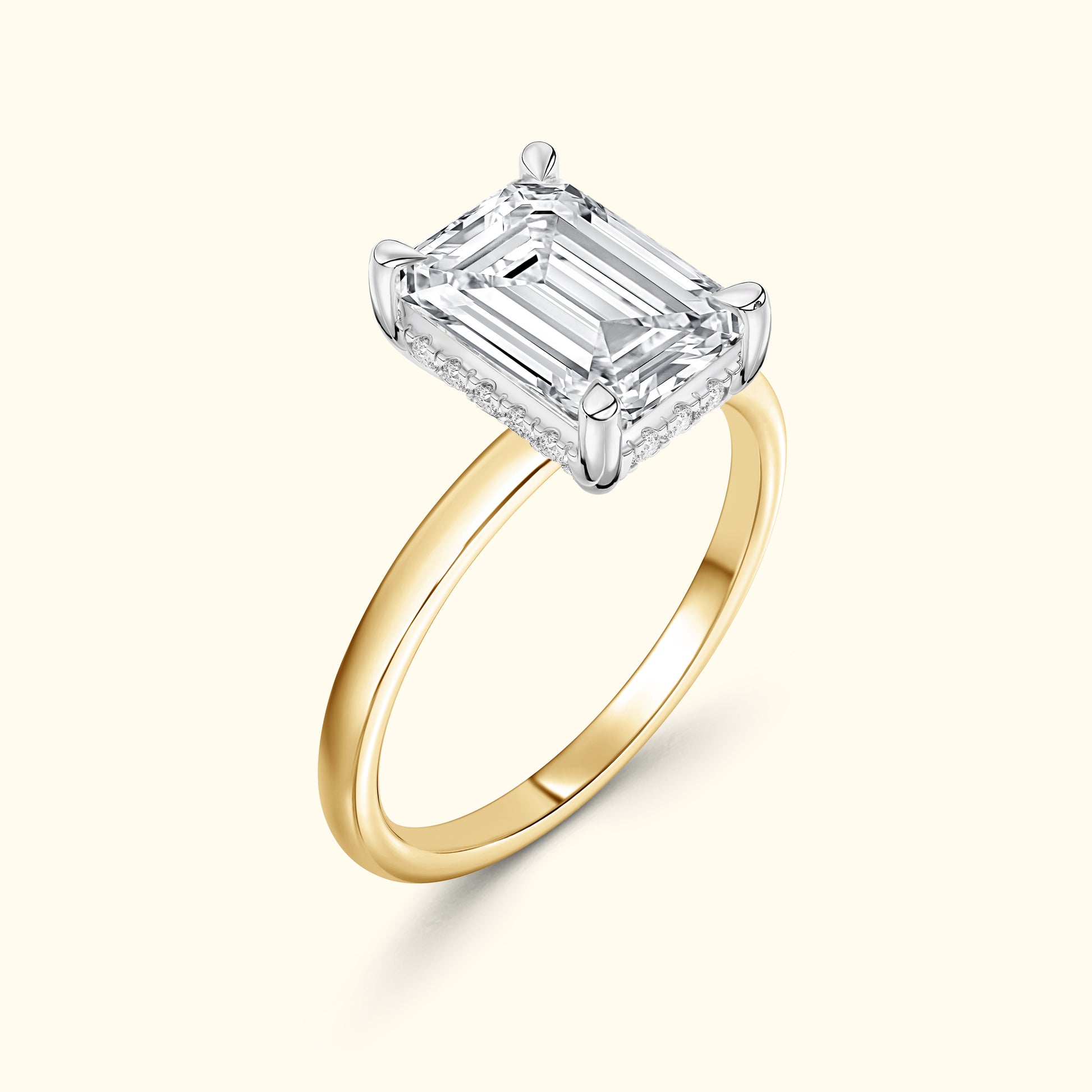 Emerald-cut diamond ring featuring a gold band and a halo of small diamonds.