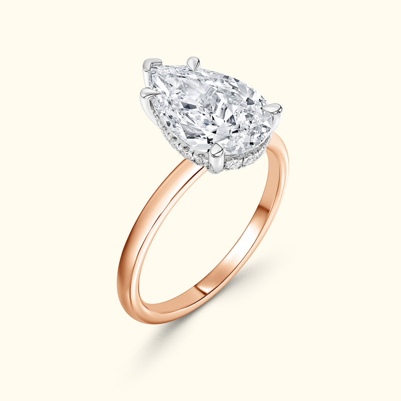 Pear-shaped diamond ring with a rose gold band and silver prongs.