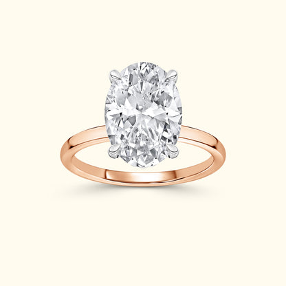 Oval diamond ring with a rose gold band on a neutral background.