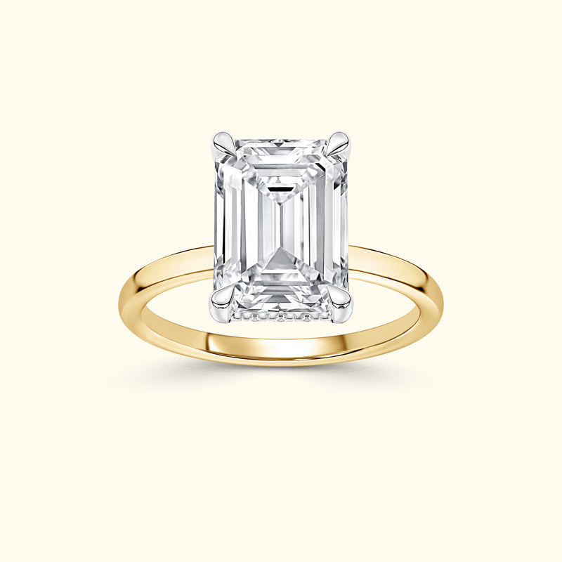 Emerald-cut diamond ring set in a sleek yellow gold band.