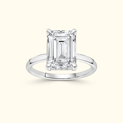 Emerald-cut diamond ring on a polished silver band against a light background.