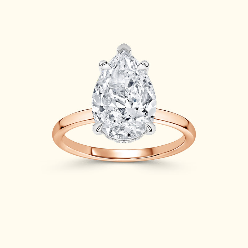 Teardrop diamond engagement ring with a rose gold band.
