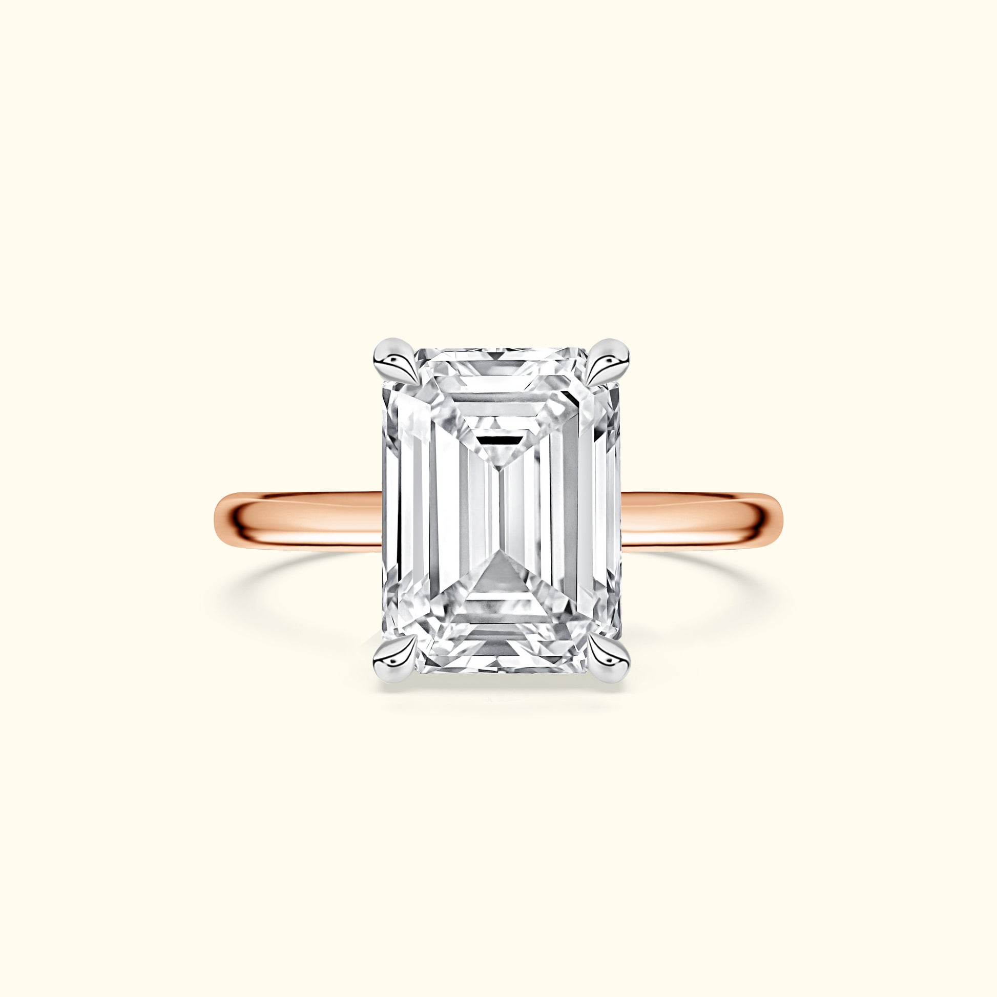 Emerald-cut diamond ring set on a rose gold band against a light background.