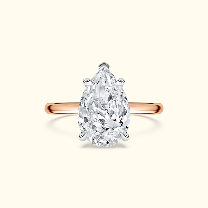 Teardrop diamond ring with a rose gold band against a light background.