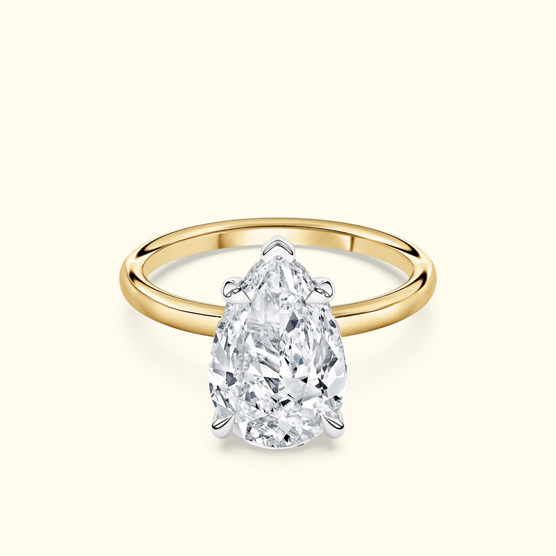 Teardrop diamond ring with a yellow gold band and a polished silver setting.