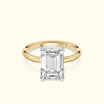 A gold engagement ring featuring a large emerald-cut diamond centerpiece.