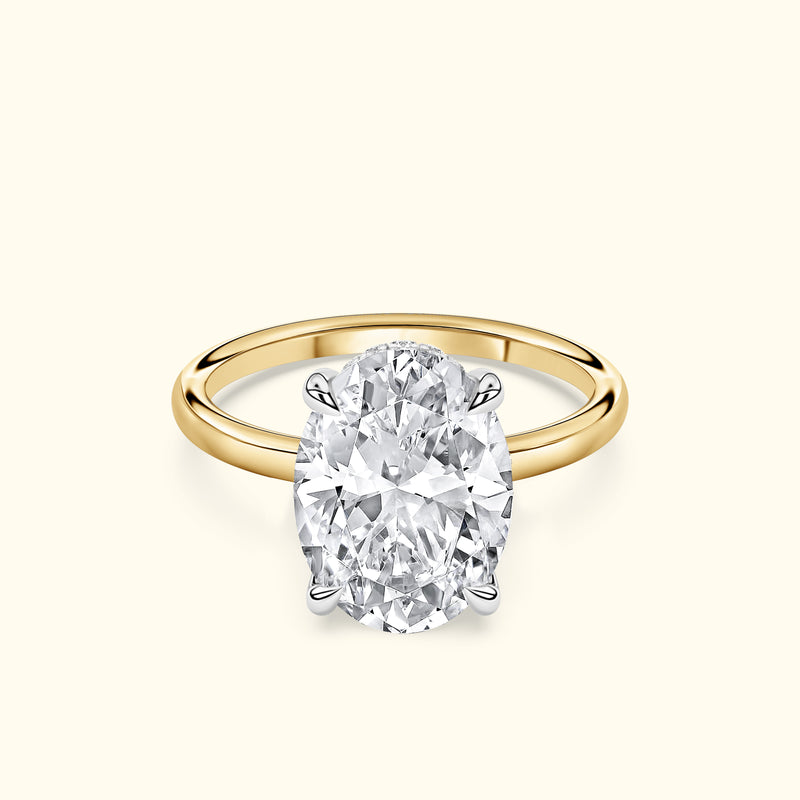 Oval diamond engagement ring with a yellow gold band and silver prongs.