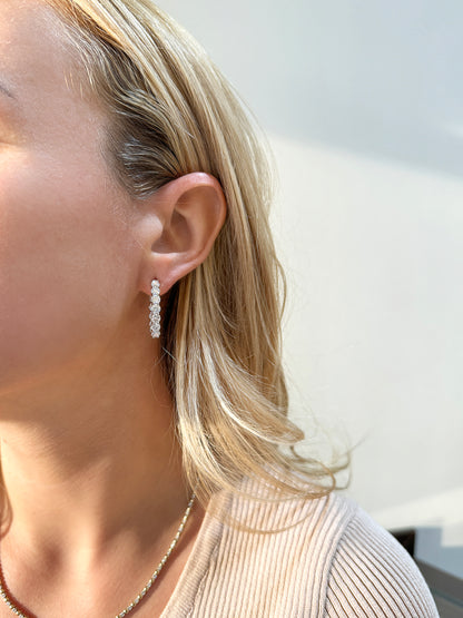 Close-up of a woman with wavy blonde hair wearing elegant diamond drop earrings.