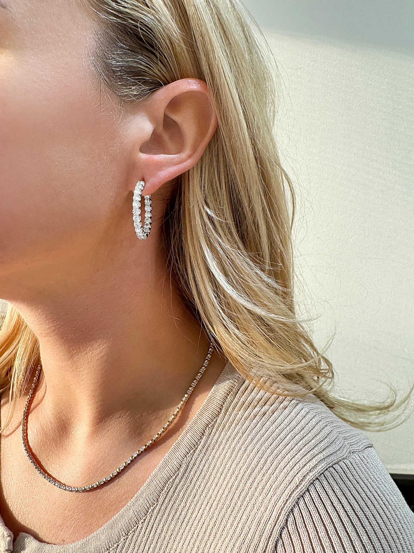 Elegant woman wearing sparkling hoop earrings and a delicate necklace.