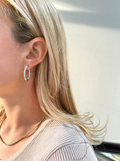 Elegant, sparkling hoop earrings worn by a woman with blonde hair, paired with a simple necklace.