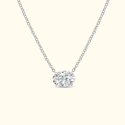 A elegant silver necklace featuring a central oval diamond pendant.
