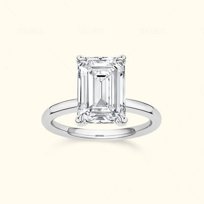 Emerald-cut diamond ring with a silver band on a neutral background.