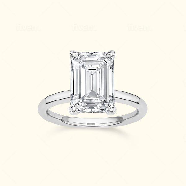 Emerald-cut diamond ring with a silver band on a neutral background.