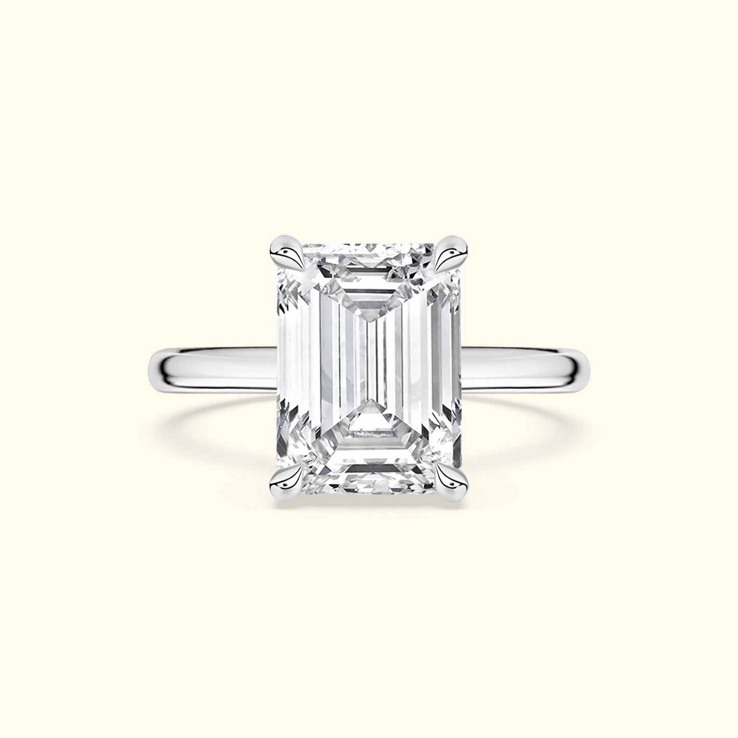 Emerald-cut diamond ring with a sleek silver band on a light background.