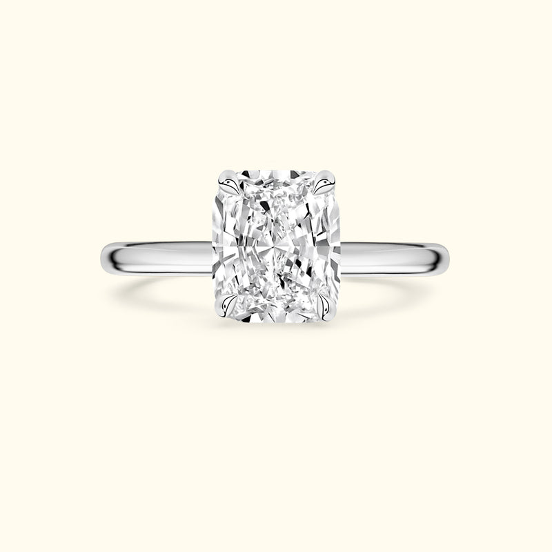 Solitaire diamond ring with a rectangular-cut center stone on a simple metal band.