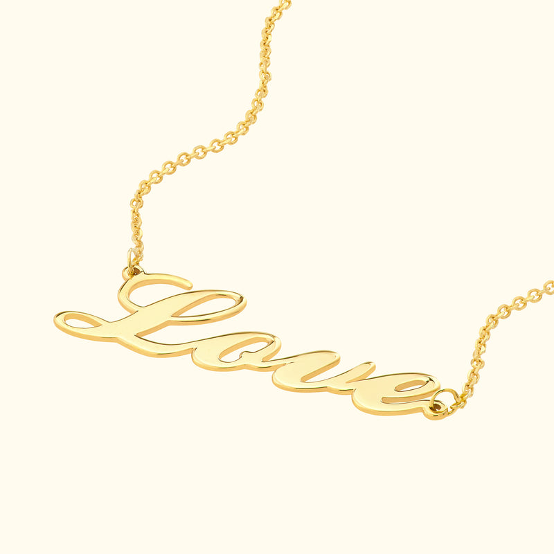Gold necklace featuring the cursive word "Love" prominently displayed.
