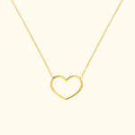 Gold heart-shaped necklace resting on a light background.