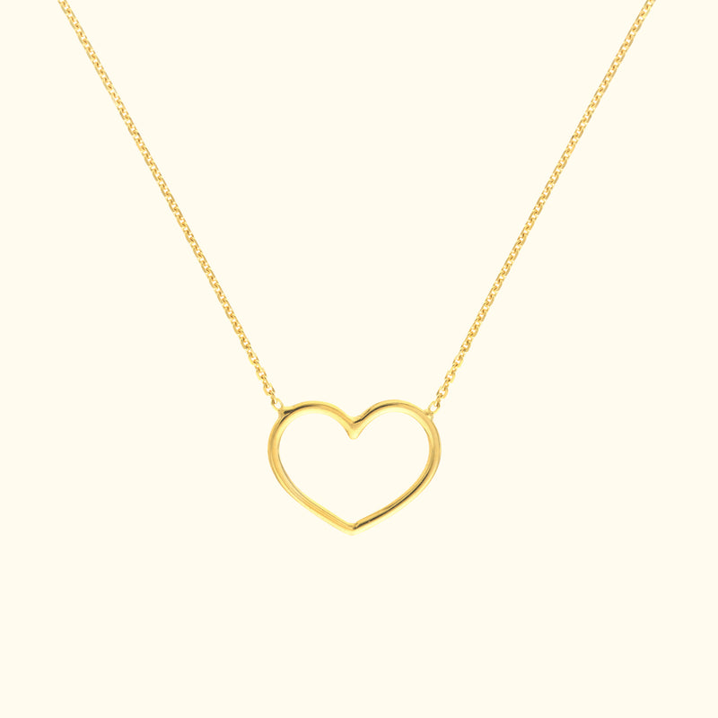 Gold heart-shaped necklace resting on a light background.