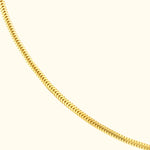 Sleek gold necklace with a flexible, linked design against a light background.