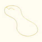 Smooth gold chain necklace with a delicate clasp, elegantly shaped and laid out flat.
