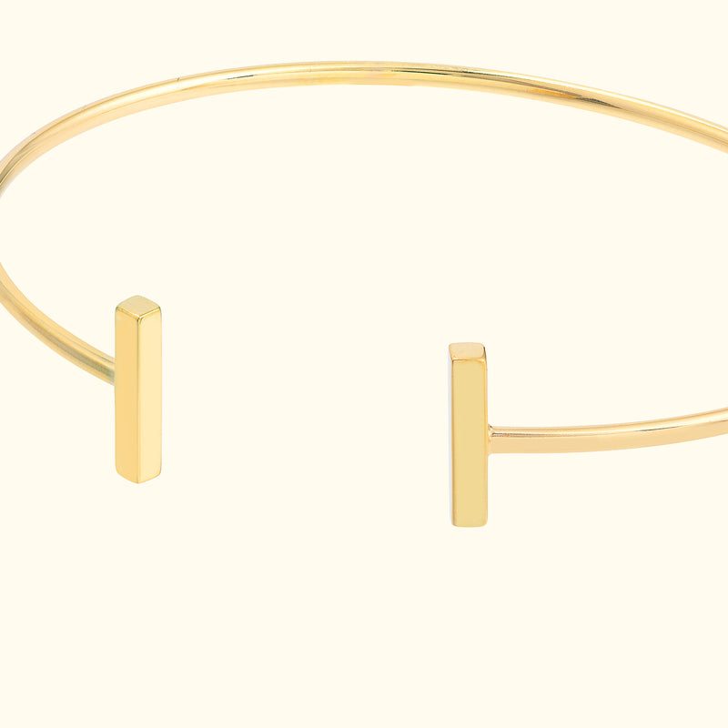 Minimalist gold cuff bracelet with two vertical bar accents.