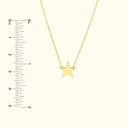 Gold star pendant necklace on a delicate chain with measurement scale.