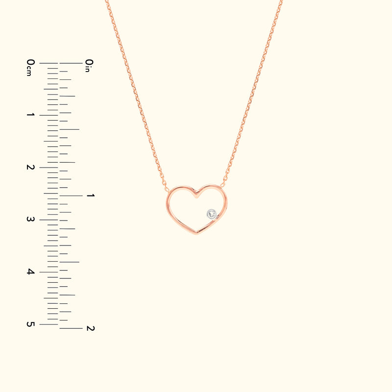 Rose gold heart necklace with a small diamond detail, displayed on a light background.
