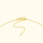 Close-up of a gold necklace clasp and chain detail on a light background.
