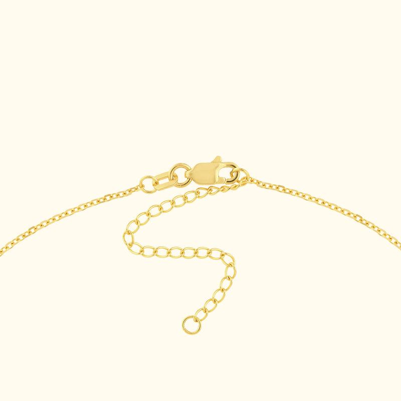 Close-up of a gold necklace clasp and chain detail on a light background.