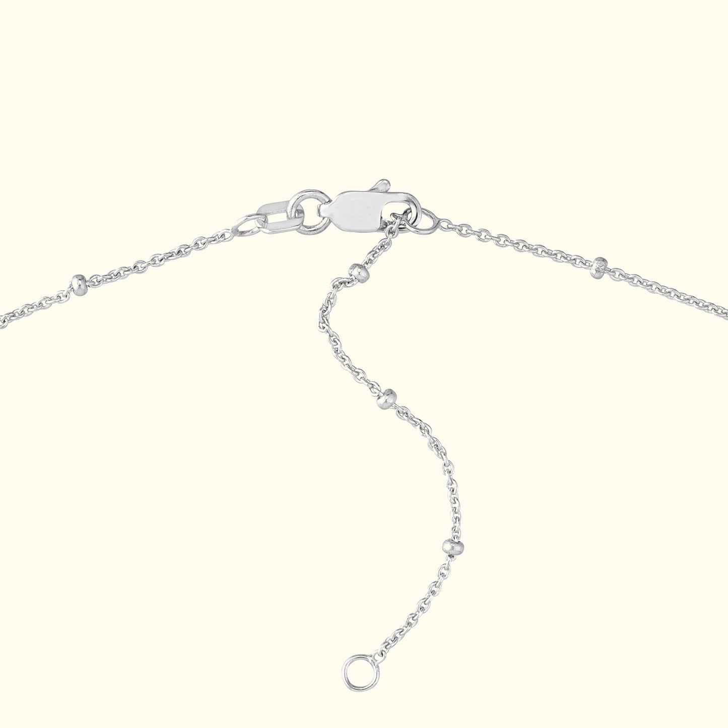 Close-up of a silver chain necklace clasp and extension links against a light background.