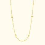 Delicate yellow gold necklace with circular gemstone accents.