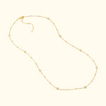 Delicate gold necklace with spaced circular charms and a clasp closure.