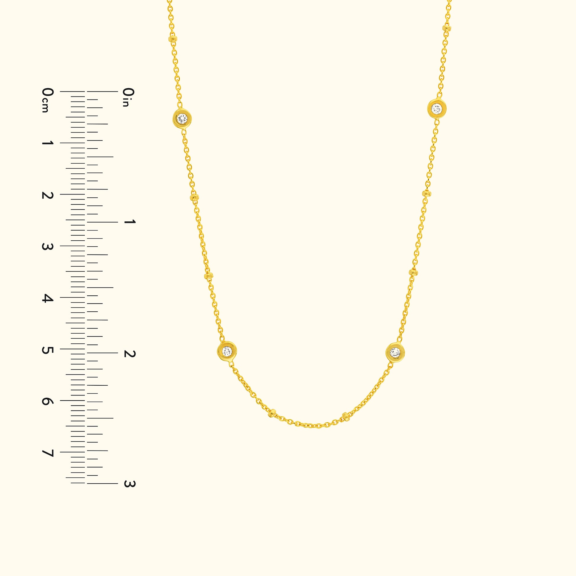 Gold necklace with small round diamond accents, displayed with a measurement scale.