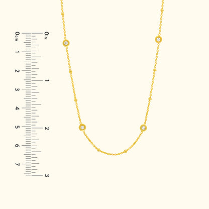 Gold necklace with small round diamond accents, displayed with a measurement scale.