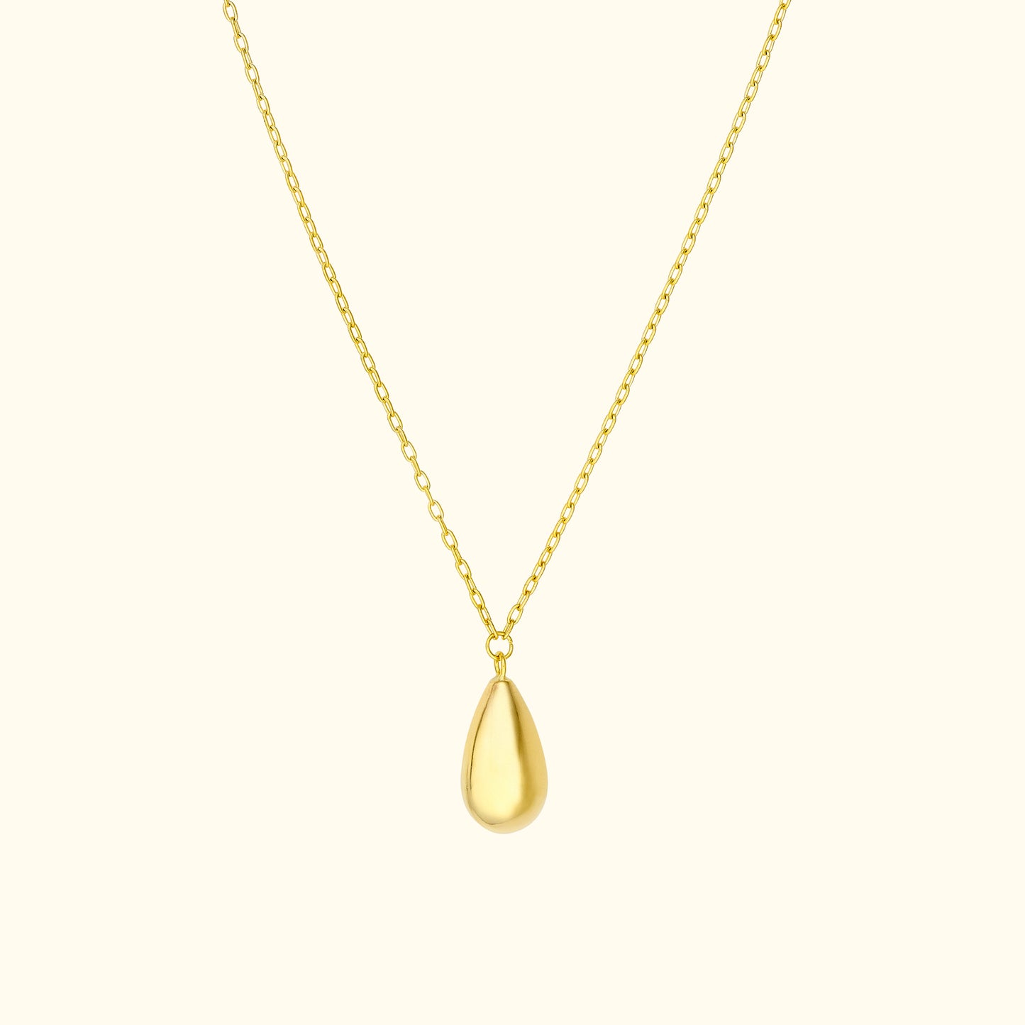 Gold teardrop pendant on a delicate chain against a light background.