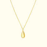 Gold teardrop pendant on a delicate chain against a light background.
