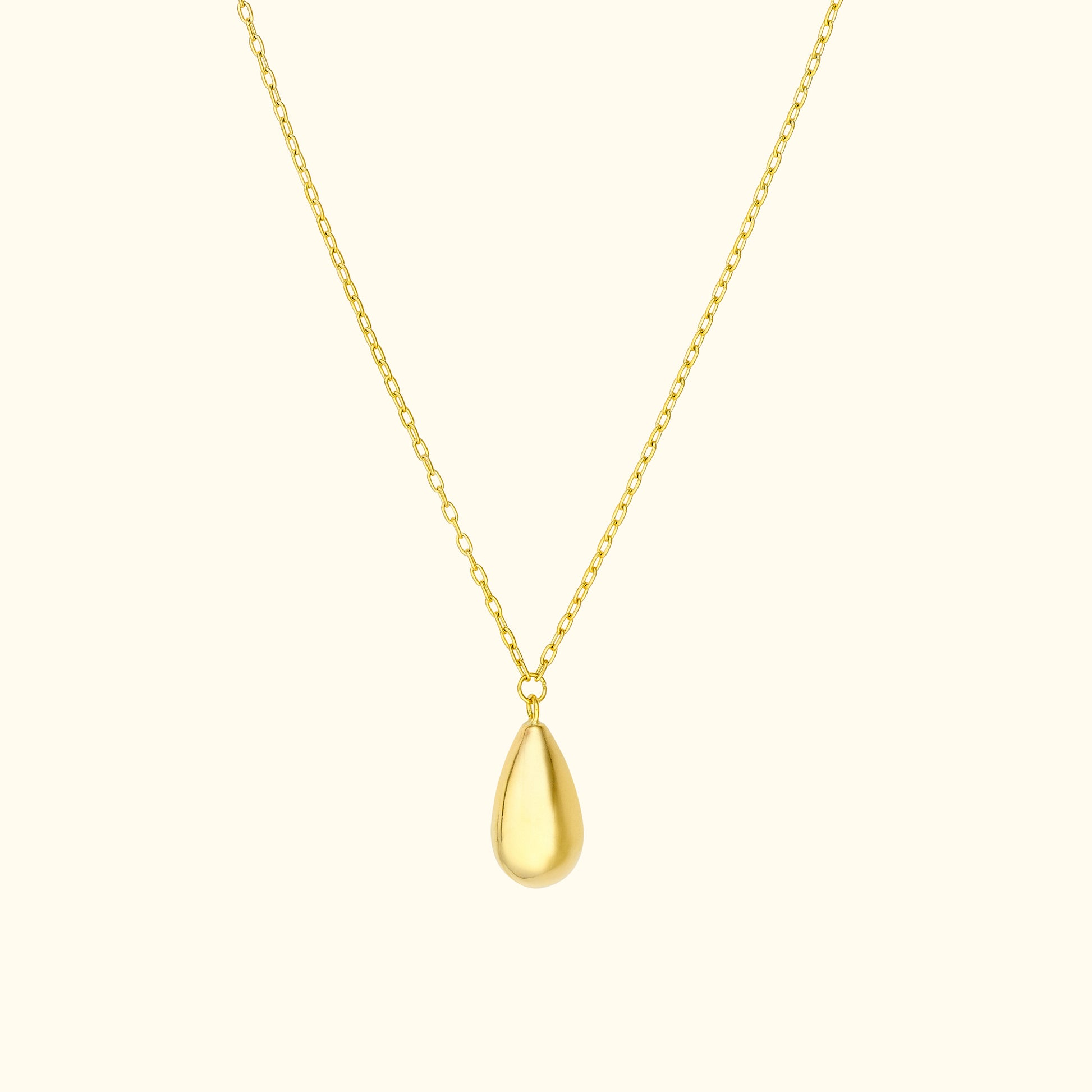 Gold teardrop pendant on a delicate chain against a light background.