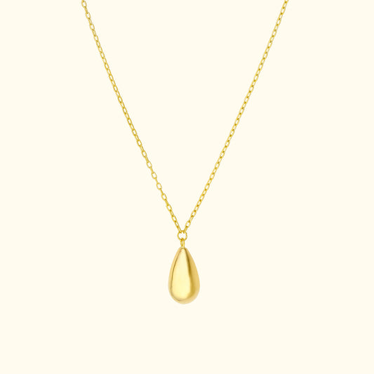 Gold teardrop pendant on a delicate chain against a light background.