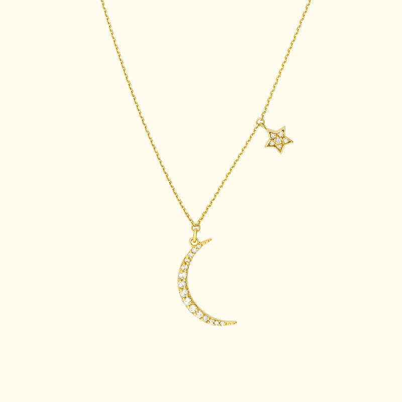 Gold necklace with a crescent moon and a star, adorned with sparkling gems.