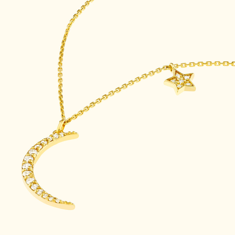 Gold necklace featuring a crescent moon and a star, adorned with sparkling gems.